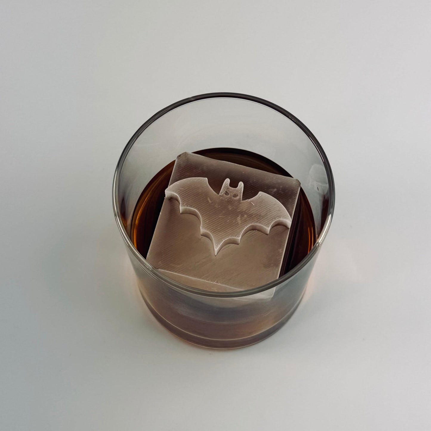Glass with a batman ice cube design on a white background