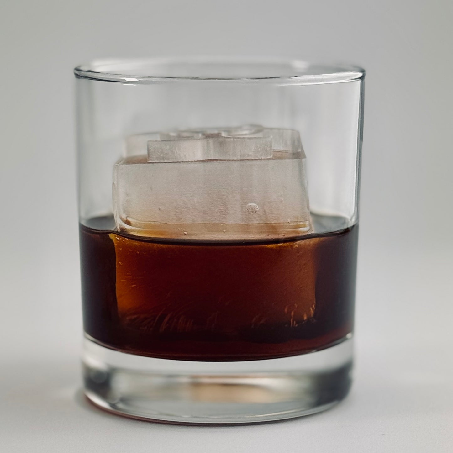 Clear ice cube with biohazard emblem in whiskey glass