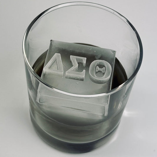 Clear glass with ice cubes featuring Greek letters on a gray background