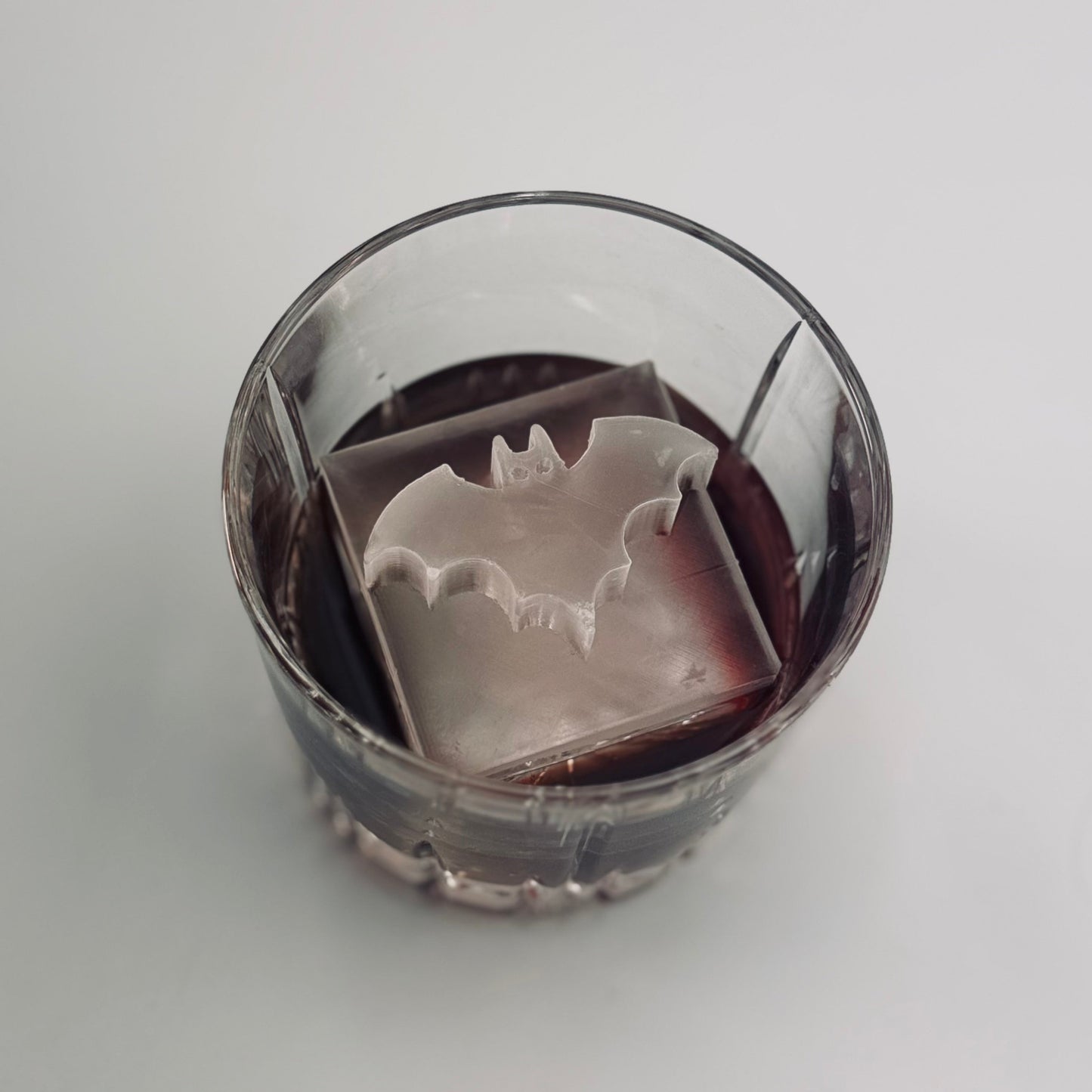 Clear glass with a metal bat-shaped object inside on a white background