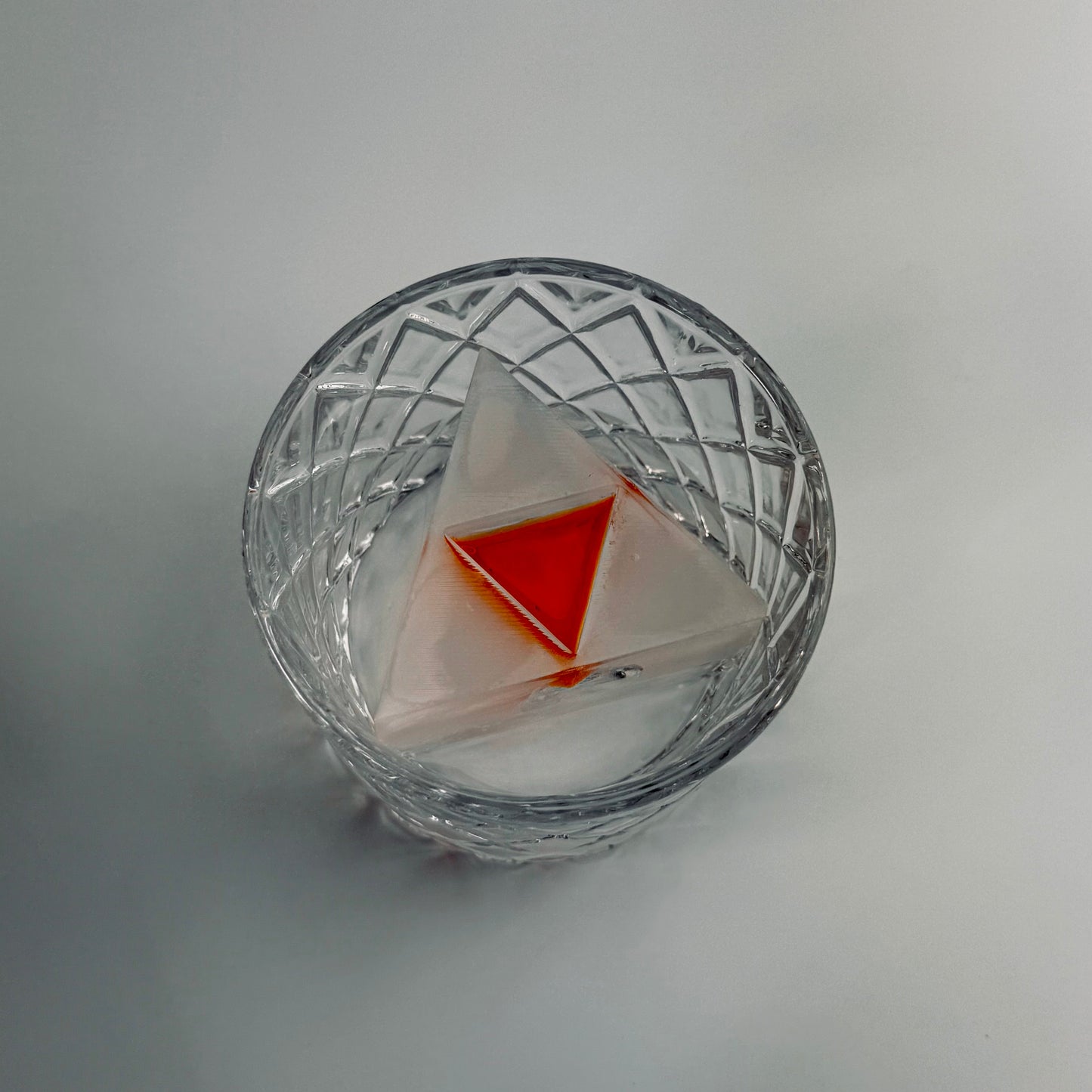 Clear glass with a Zelda Triforce inside on a light gray background
