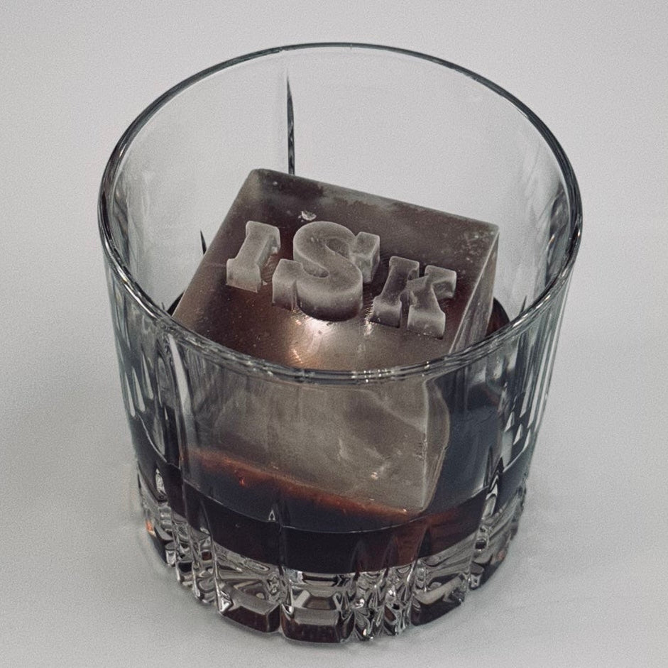 Clear glass with a ice cube monogram on top on a white background