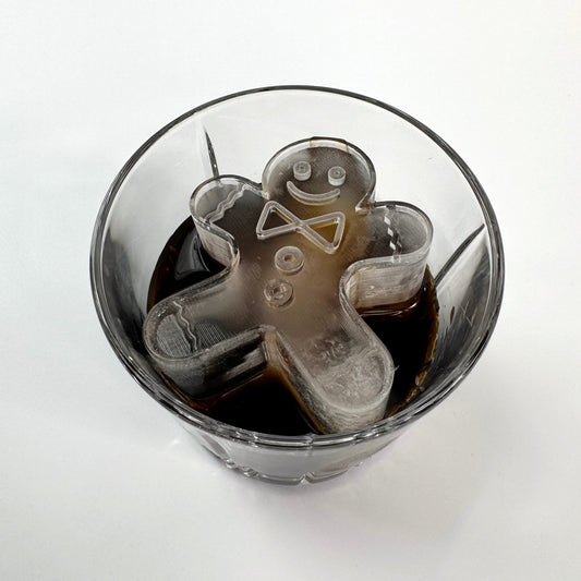A clear ice mold in the shape of a gingerbread man with ice cubes inside a glass.