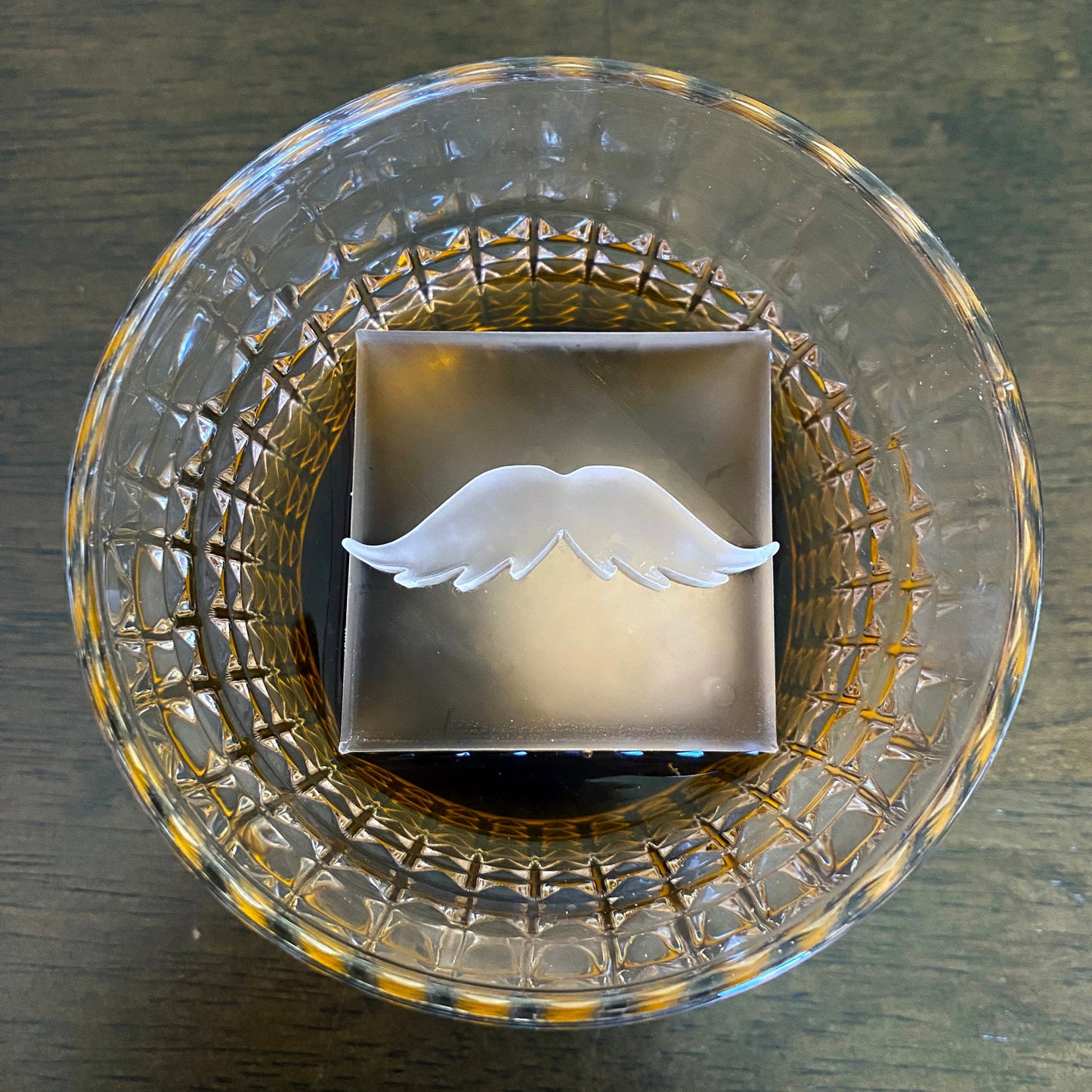 Clear glass with a decorative mustache ice on a wooden surface