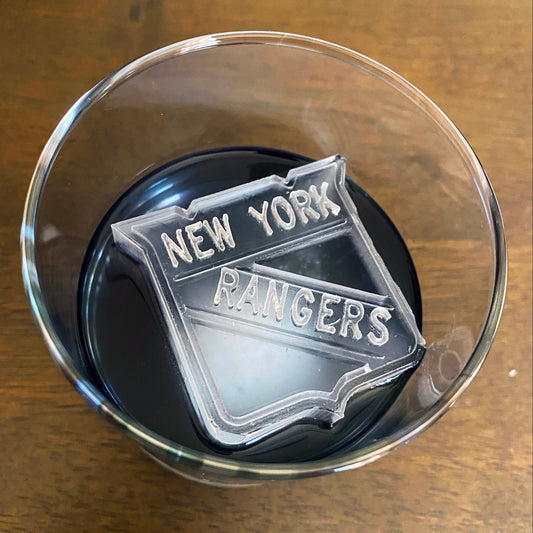 A clear ice mold with the text 'NEW YORK RANGERS' on it, placed inside a glass.