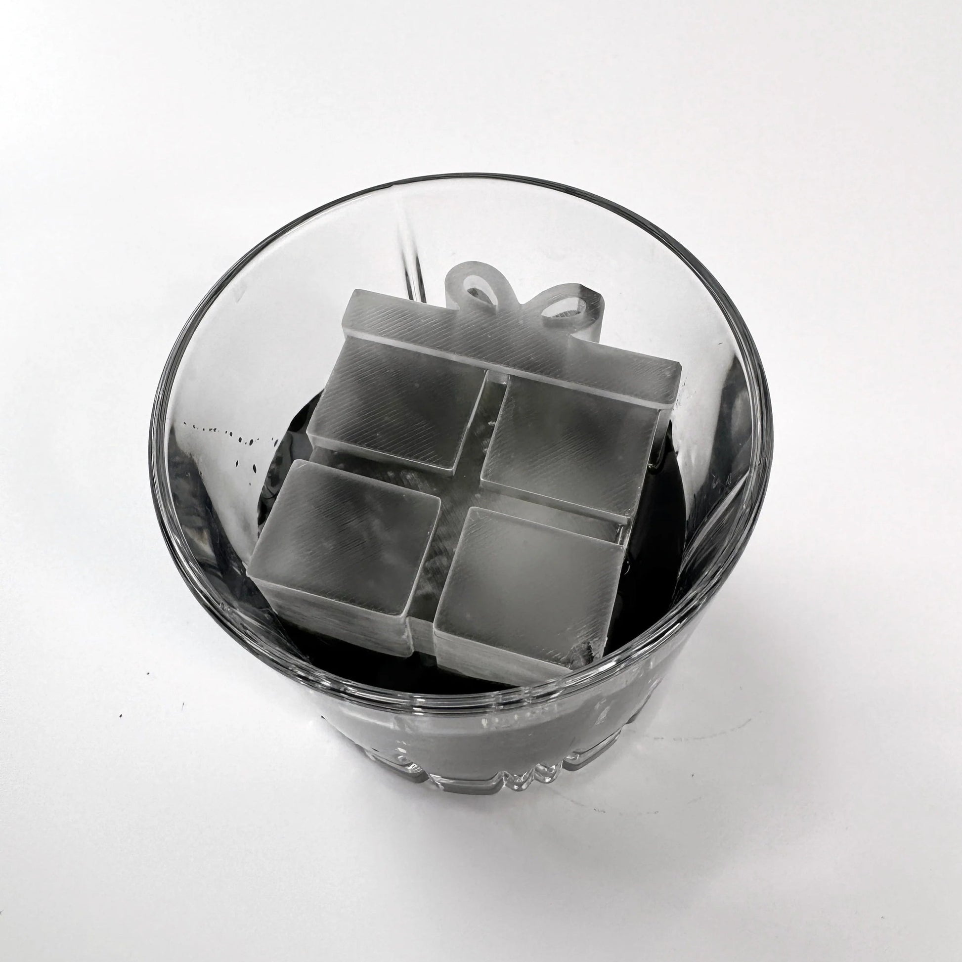 Clear glass container with metal cube puzzle on a white background