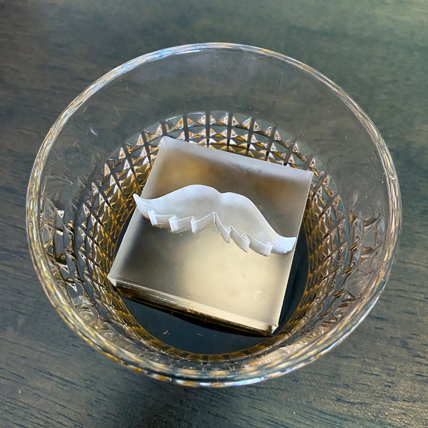 Clear glass drink with a mustache ice cube