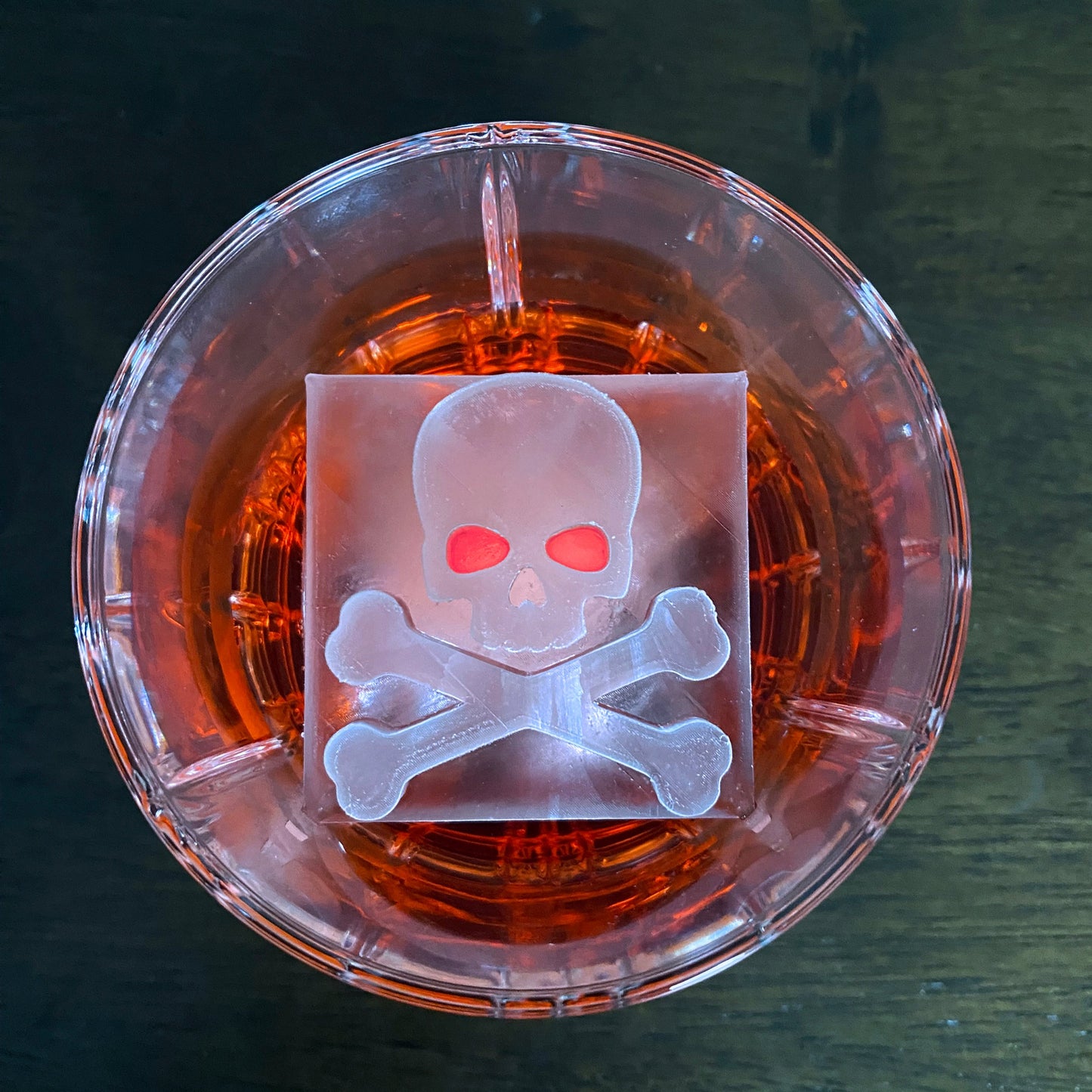 Clear container with a skull and crossbones design on a dark surface