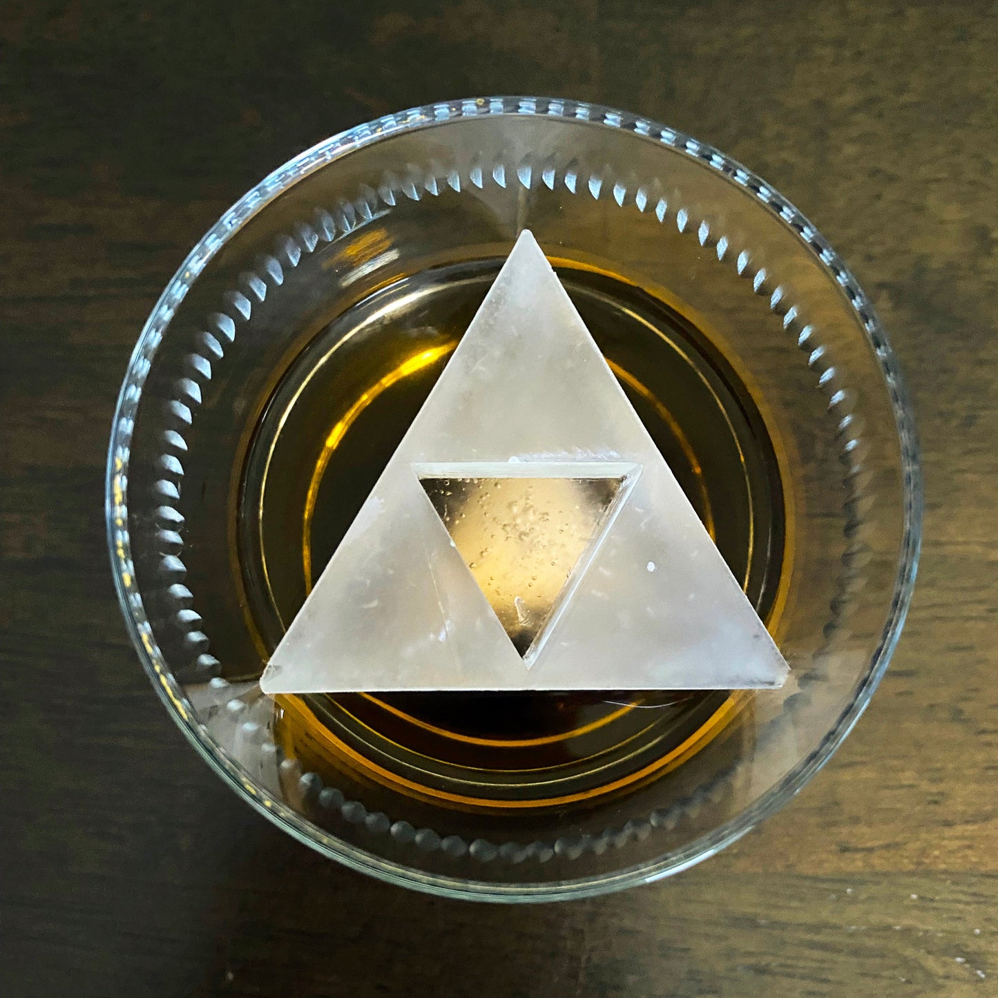 Triforce triangle in a glass drink on a wooden surface. Zelda inspired