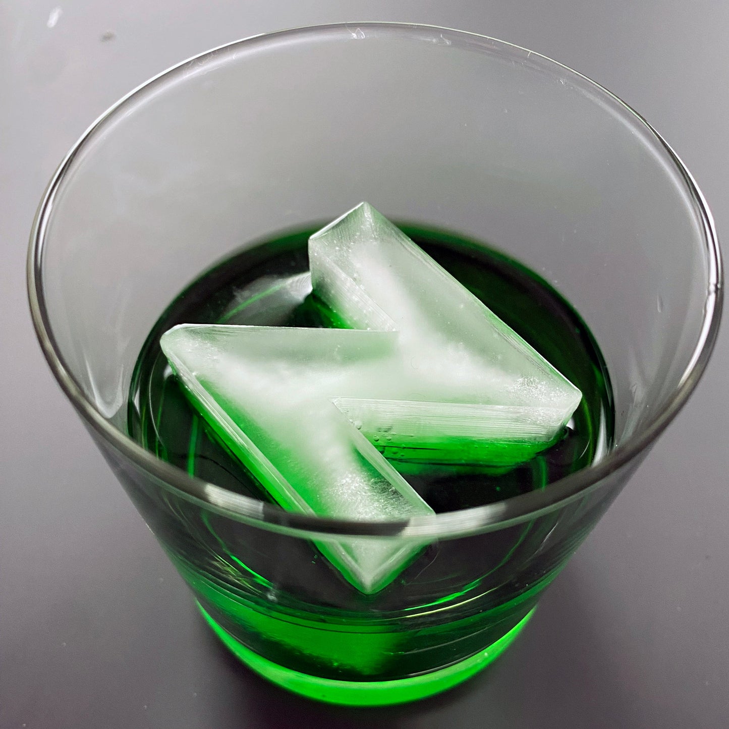 An ice tray with a silicone mold in the shape of the letter 'N', with water filling the tray, set on a white background.
