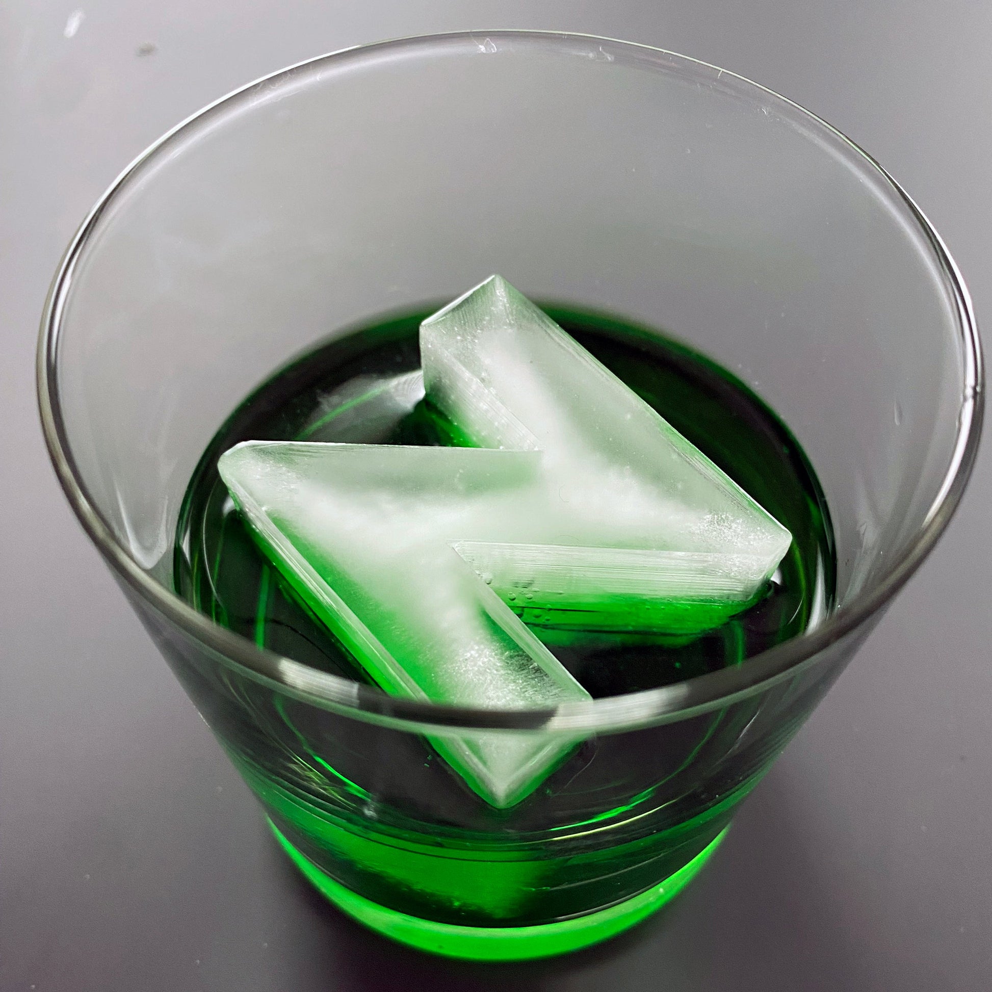 An ice tray with a silicone mold in the shape of the letter 'N', with water filling the tray, set on a white background.