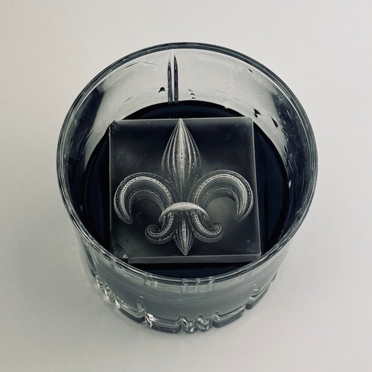Clear glass with a fleur-de-lis design on ice cube on a white background