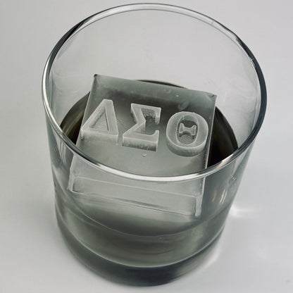 Clear glass with ice cubes featuring Greek letters on a gray background