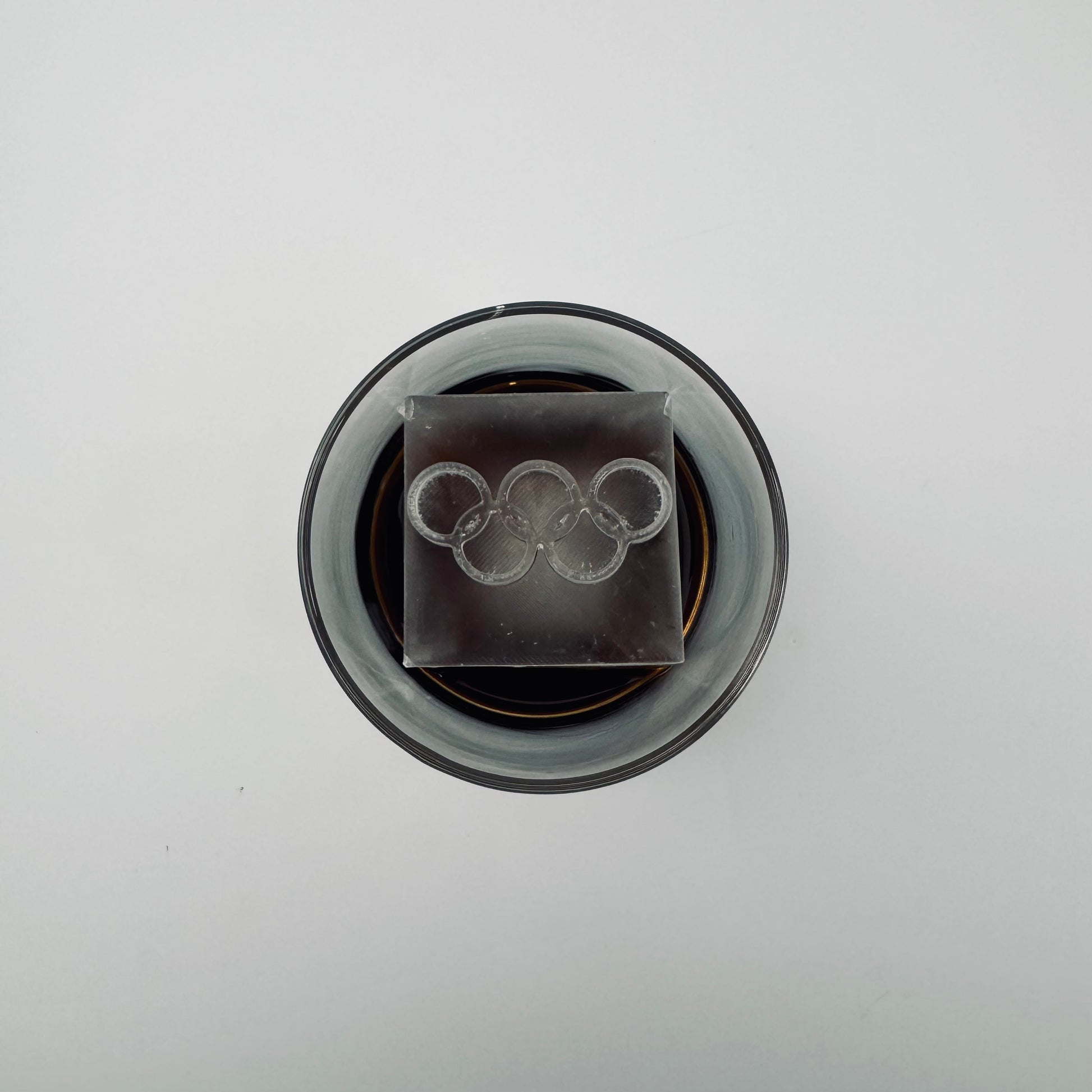 Ice cube with Olympic rings design in a glass container on a white background