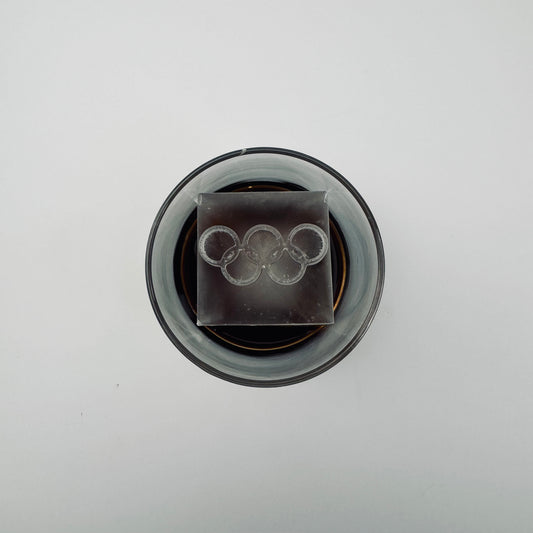 Ice cube with Olympic rings design in a glass container on a white background