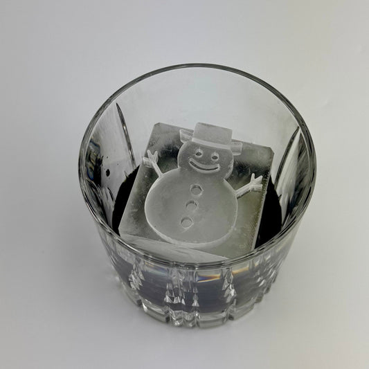 Clear glass with a snowman-shaped ice inside on a white background