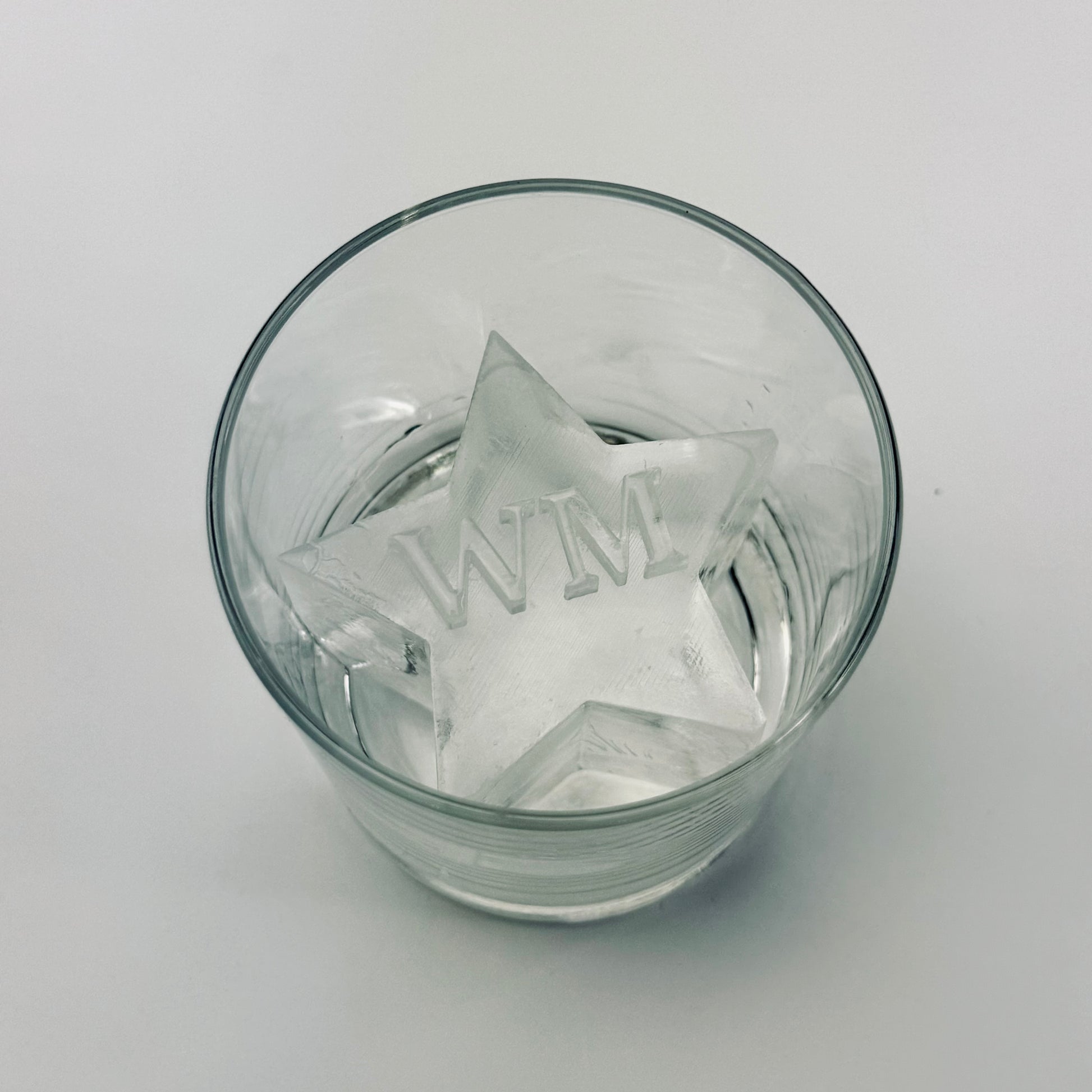 Clear glass with star ice cubes inside on a light gray background