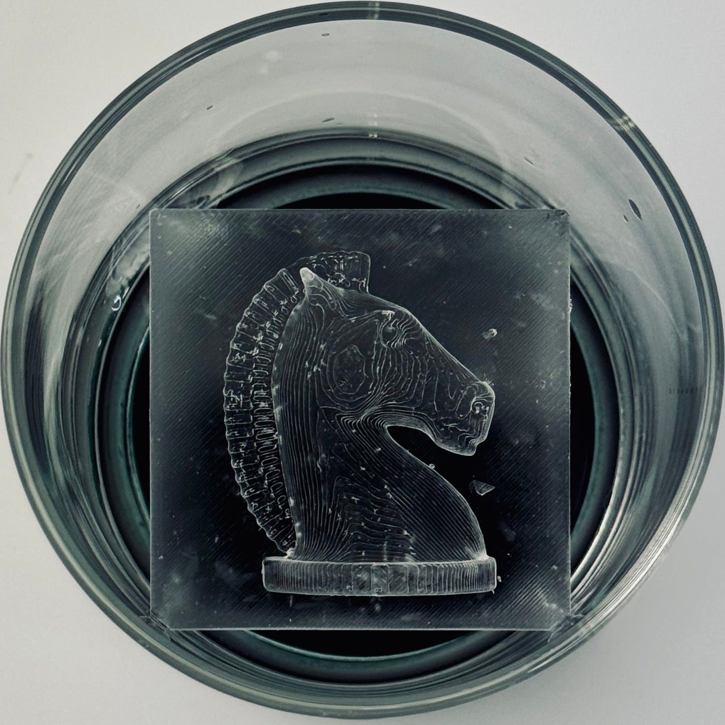 Ice Knight chess piece in a glass container on a light gray background