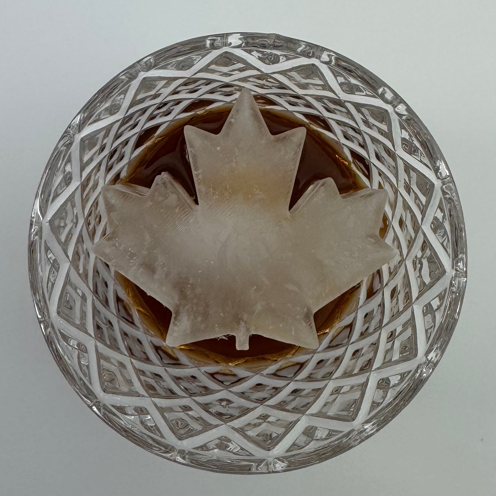Maple leaf-shaped ice on a decorative glass bowl with a white background