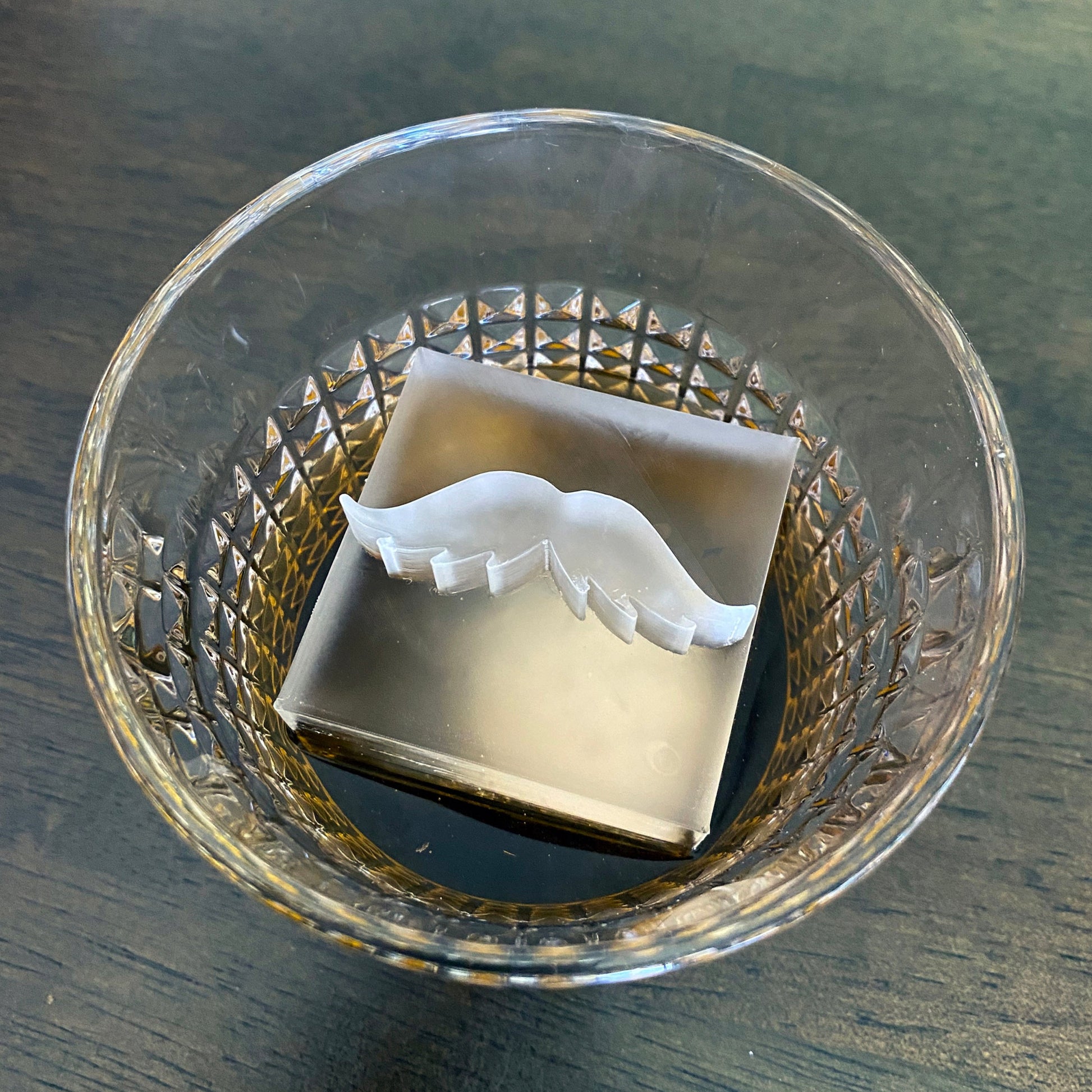 Clear glass drink with a mustache ice cube