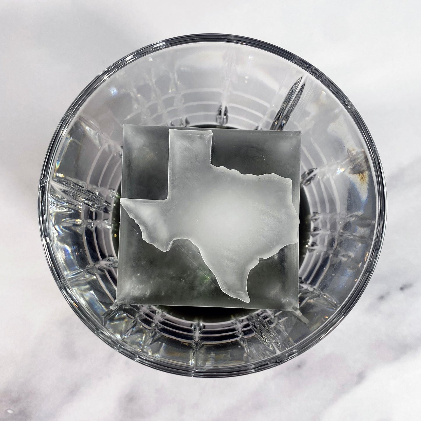 Ice in the shape of Texas on top of an ice cube
