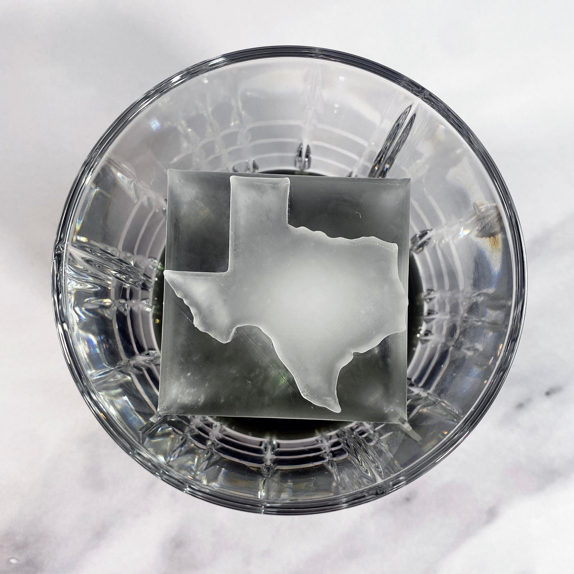 Ice in the shape of Texas on top of an ice cube